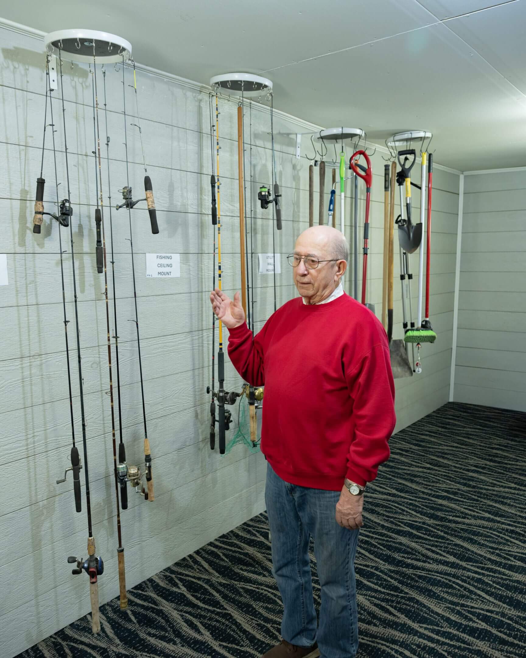 Elderly man beside wall of hanging fishing rods